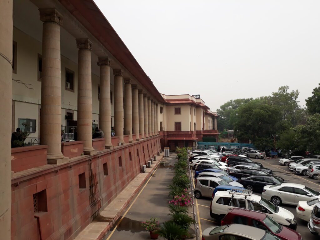 Side view of the Supreme Court of India building in New Delhi, featuring its colonnaded façade designed by architect Ganesh Bhikaji Deolalikar.