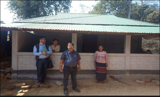 A rural family and officials standing in front of a newly built pucca house under PMAY-G.