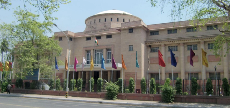 Front view of the National Museum building in New Delhi with Indian flag and colorful flags at the entrance.