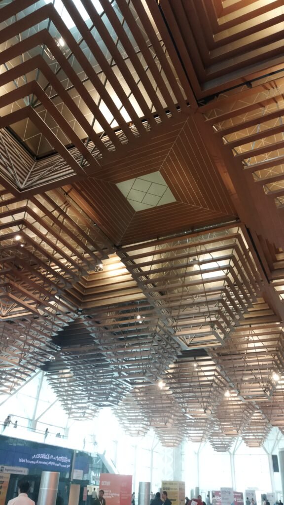 Geometric ceiling design of Yashobhoomi convention centre featuring intricate layered wooden patterns and ambient lighting.