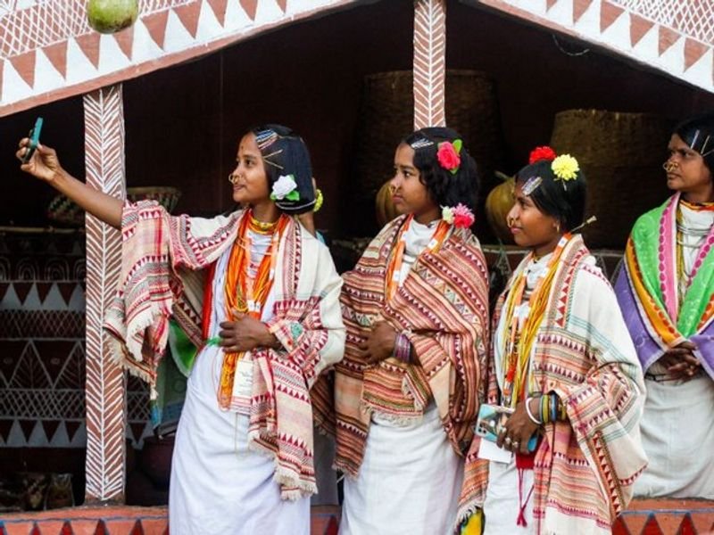 Tribal women dressed in traditional attire take a selfie during the ‘Silent Conversation: From Margins to the Centre’ Tribal Art Exhibition in New Delhi.