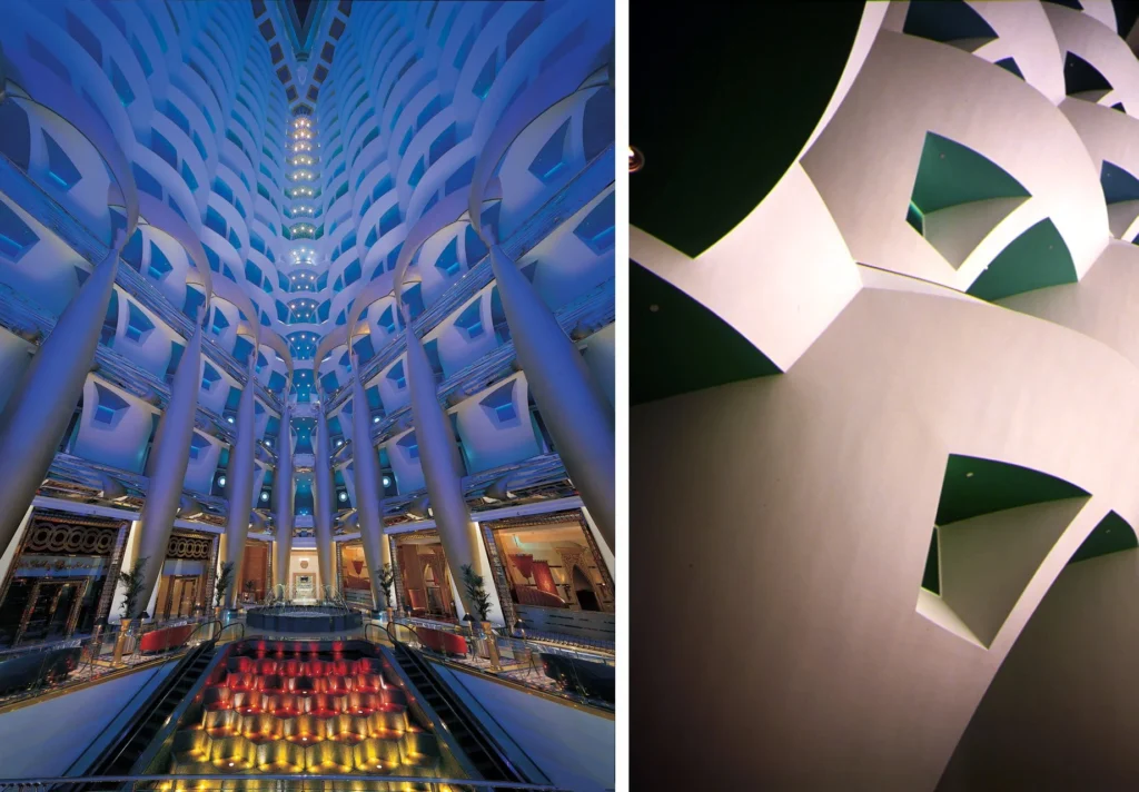 The soaring multi-storey atrium of the Burj Al Arab illuminated in blue tones, showcasing its layered balconies and grand interior design.