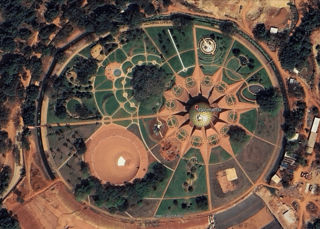 Aerial satellite view of Matrimandir showing the central golden sphere, surrounding twelve petals, meditation gardens, and landscape layout of Auroville’s Peace Area.