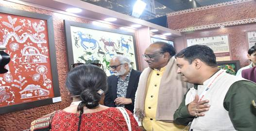 Visitors and officials observing traditional Warli and tribal art pieces displayed at the Ministry of Culture pavilion.