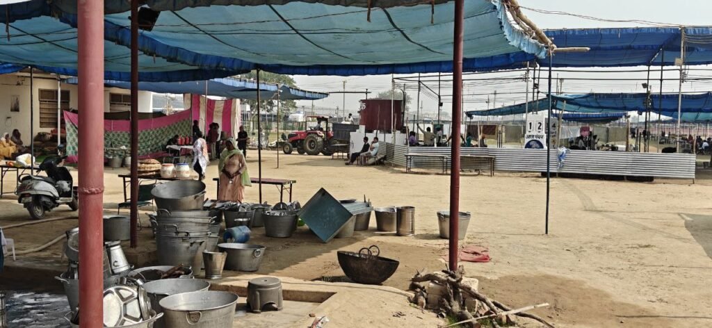 Volunteers prepare food and manage kitchen operations under shaded canopies at the Sant Nirankari Samagam site in Samalkha.