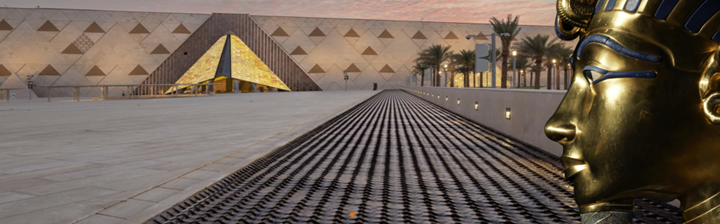 Aerial view of the Grand Egyptian Museum showcasing its triangular façade with the Giza Pyramids visible in the background.