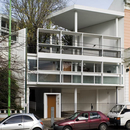 Front façade of the Curutchet House in La Plata, Argentina, showing pilotis, free façade, open terraces, and modernist glass panels.