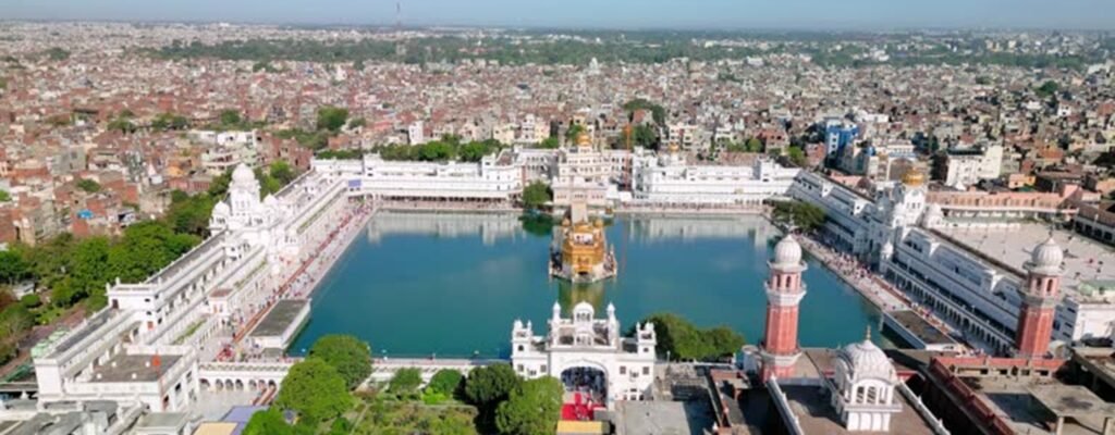 Aerial view of the Golden Temple complex and surrounding walled city of Amritsar, showing the sacred Sarovar as the urban core with dense historic neighborhoods around it.