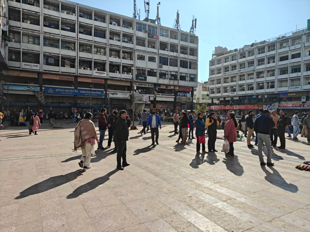 People gathering in the central open plaza surrounded by modernist commercial buildings at Nehru Place, Delhi