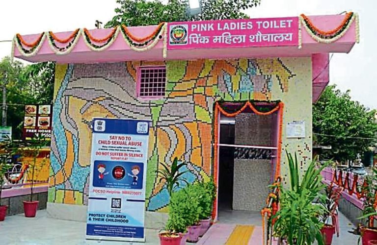 Pink ladies toilet facility with mosaic artwork, signage for women’s sanitation and safety, and accessible entrance in a public urban space in Delhi.