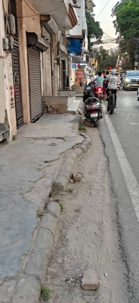 Uneven and broken footpath with scooter encroachment in Delhi residential colony
