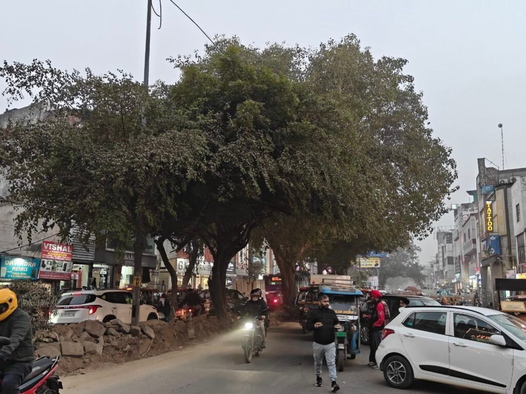 Traffic congestion and mixed pedestrian movement on Jail Road between Tilak Nagar and Hari Nagar in West Delhi