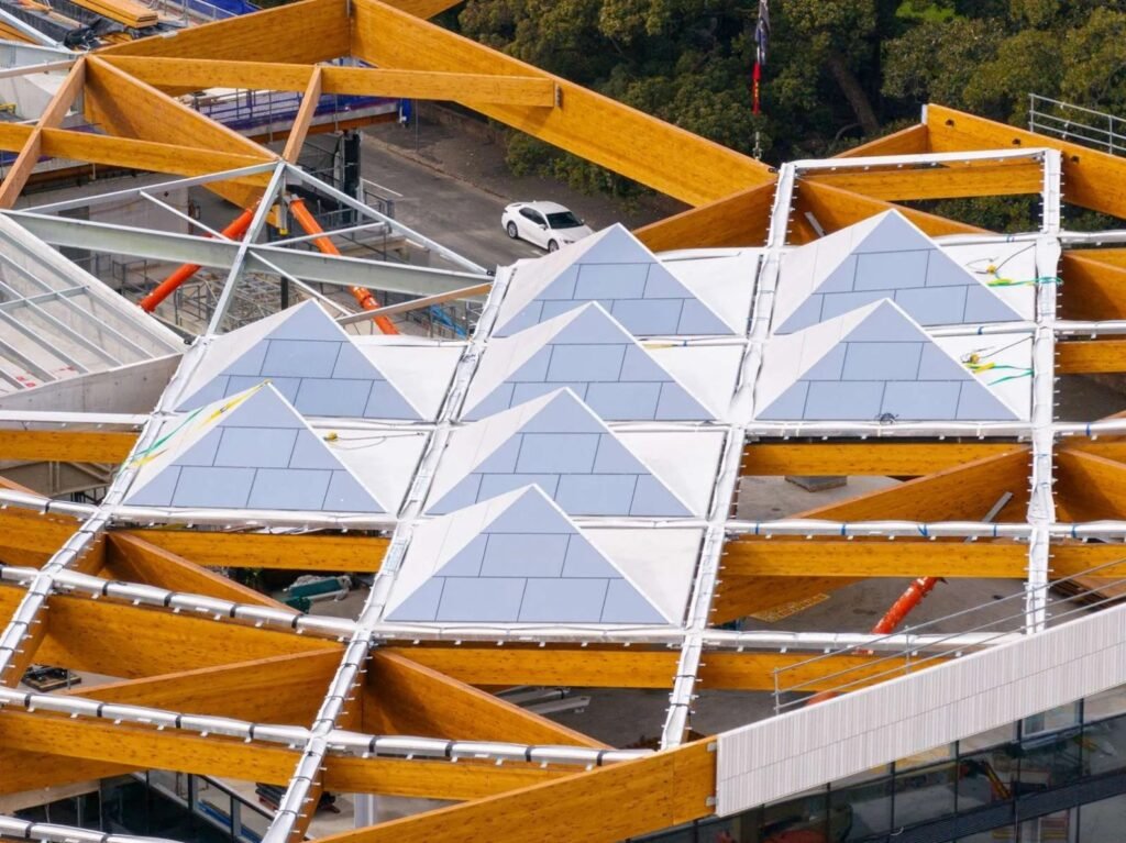 Aerial view of the Sydney Fish Market’s 200-metre timber and aluminium canopy roof under construction, showing triangular roof modules and structural framing.