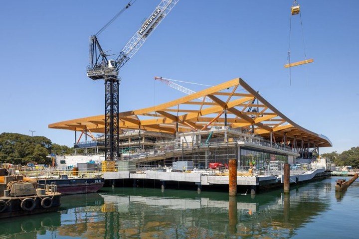 Construction view of the Sydney Fish Market showing the large-span timber roof frame and aluminium roof panels being installed along the waterfront.