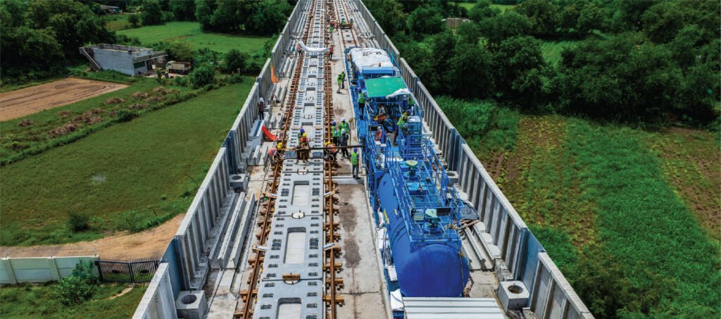 Mumbai–Ahmedabad bullet train track construction on elevated viaduct with workers installing high speed rail infrastructure in Gujarat