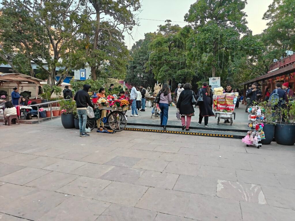 Entry threshold at Dilli Haat INA with informal vendors carts and pedestrian movement