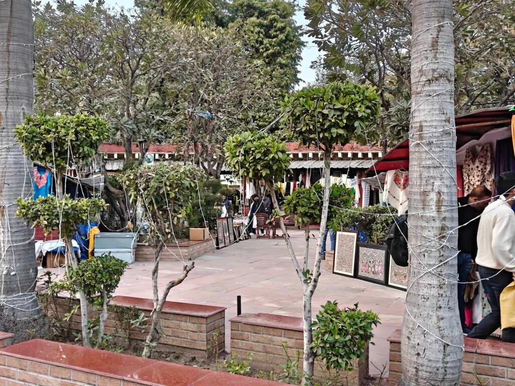 Landscaped courtyard with trees and craft displays at Dilli Haat INA