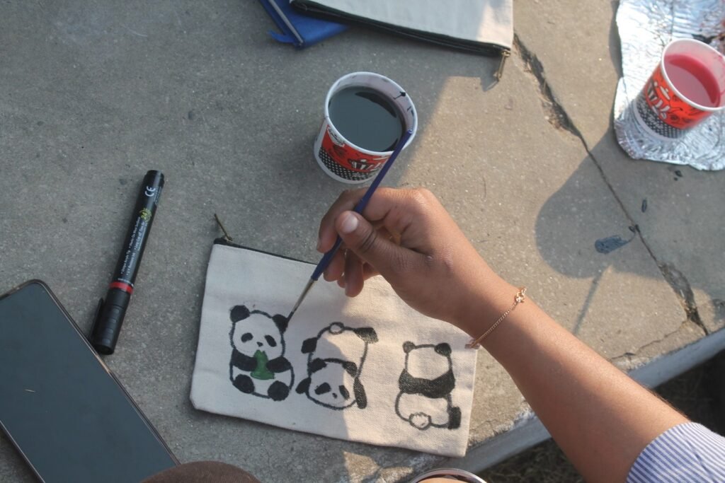 Student painting panda design on canvas pouch during NEXUS workshop