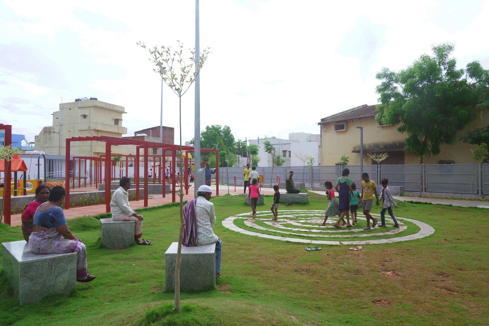 Residents and children using the community seating and open lawn area at Community Plug.