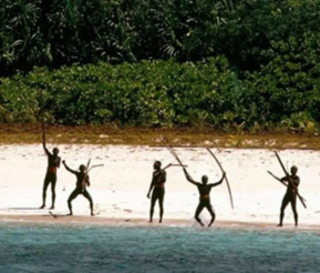 GREED VS NEED: Indigenous people standing on a beach with the forest landscape in the background