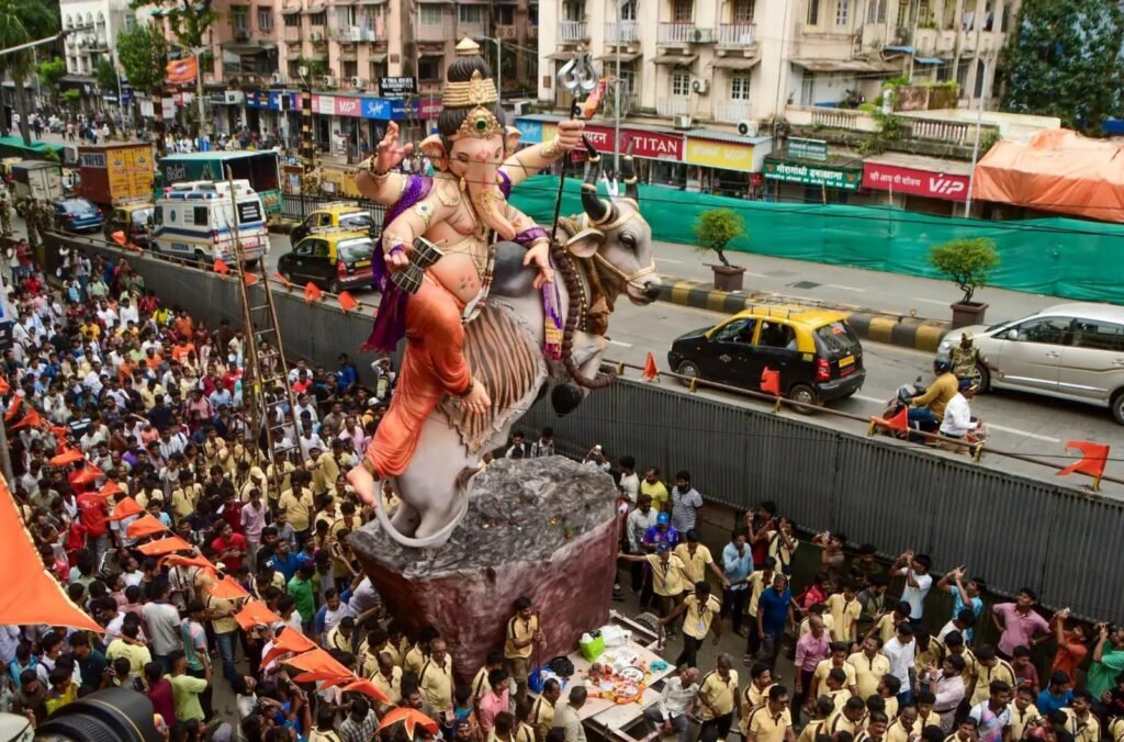 Ganesh idol procession through a crowded Mumbai street during Ganesh Utsav